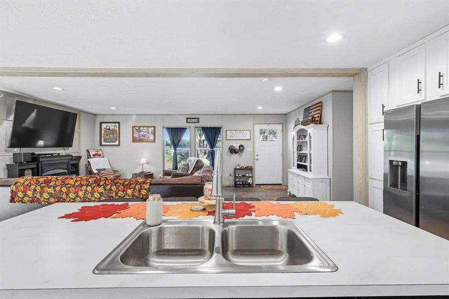 Kitchen featuring open floor plan, light countertops, stainless steel fridge with ice dispenser, recessed lighting, and white cabinets Kitchen featuring open floor plan, light countertops, stainless steel fridge with ice dispenser, recessed lighting, and white cabinets
