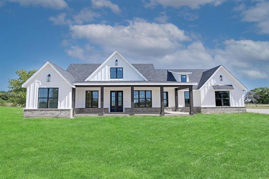 Back of property with french doors, a lawn, roof with shingles, and board and batten siding