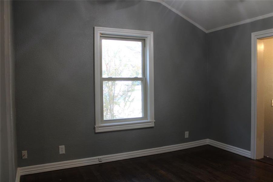 Spare room featuring dark wood-style flooring and crown molding Spare room featuring dark wood-style flooring and crown molding