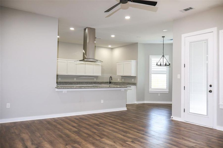 Kitchen with dark wood finished floors, white cabinetry, island exhaust hood, a peninsula, and recessed lighting