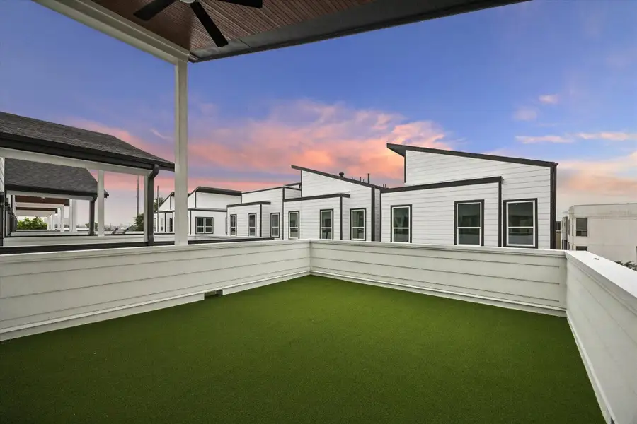 Modern rooftop terrace with artificial grass, surrounded by sleek white paneling. Offers ample space for outdoor relaxation with a stylish ceiling fan for added comfort. Modern rooftop terrace with artificial grass, surrounded by sleek white paneling. Offers ample space for outdoor relaxation with a stylish ceiling fan for added comfort.