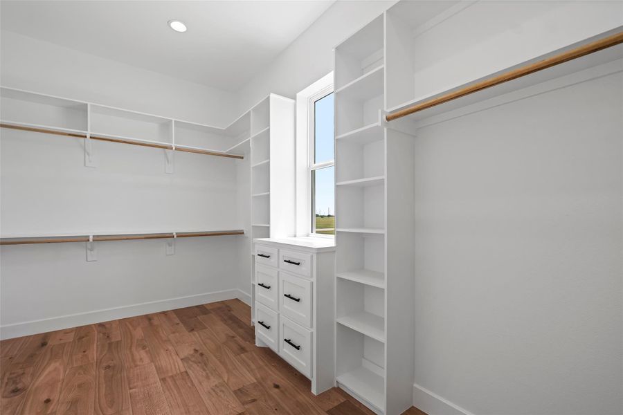 Spacious Hers walk-in closet in the primary bedroom, featuring ample shelving and natural light.
