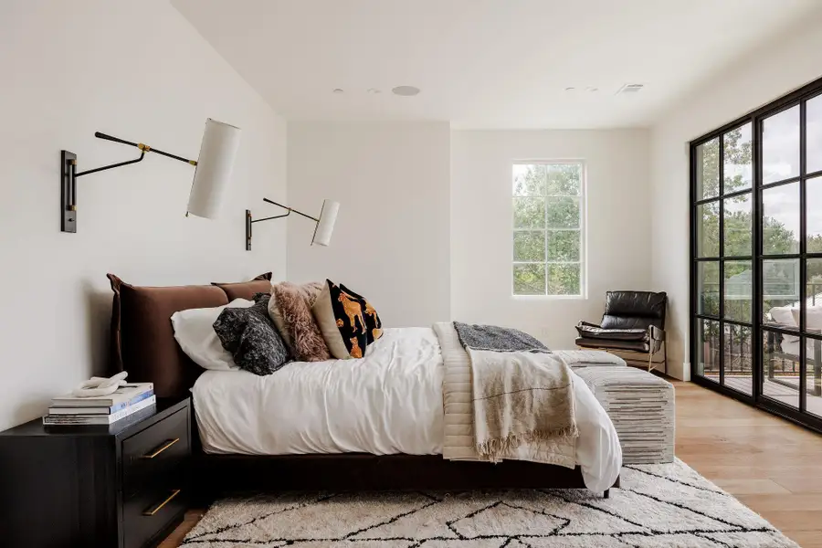 The primary suite offers serenity and scale with high ceilings, soft natural light, custom sconces, and calming treetop views. The primary suite offers serenity and scale with high ceilings, soft natural light, custom sconces, and calming treetop views.