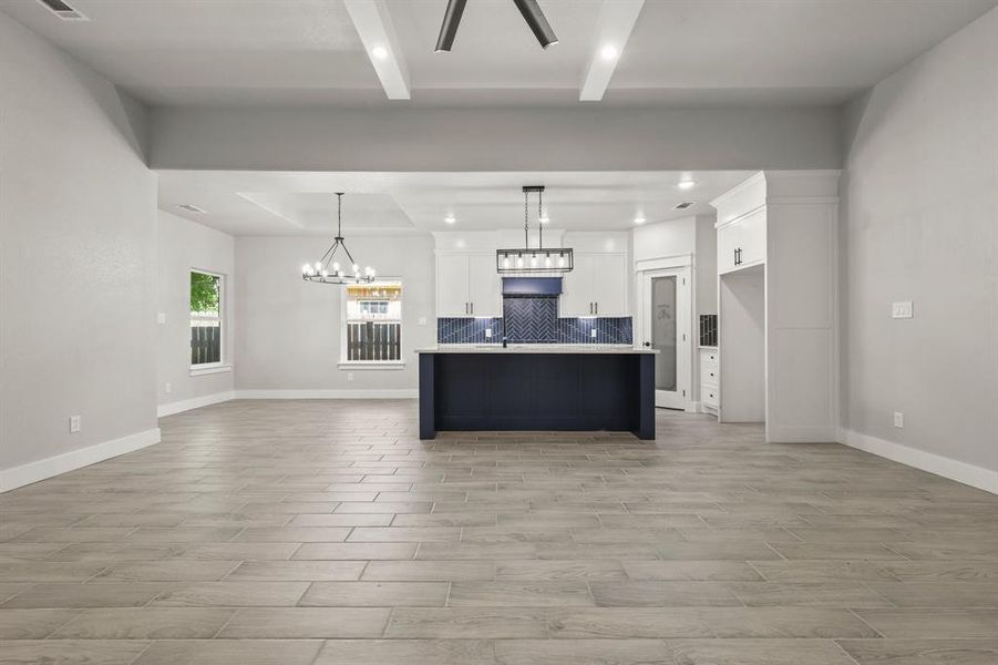 Kitchen featuring open floor plan, tasteful backsplash, white cabinets, light wood-type flooring, and recessed lighting
