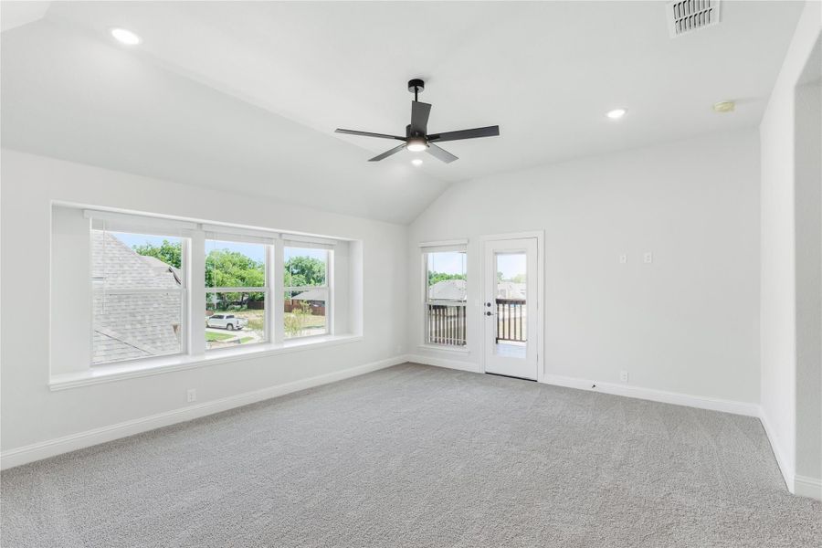 Empty room with vaulted ceiling, ceiling fan, gray carpet, large windows, and a glass door to the exterior. Empty room with vaulted ceiling, ceiling fan, gray carpet, large windows, and a glass door to the exterior.