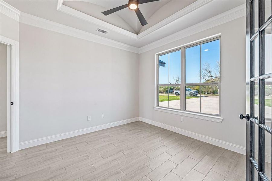 Unfurnished room featuring a raised ceiling, ornamental molding, light wood-style floors, and ceiling fan