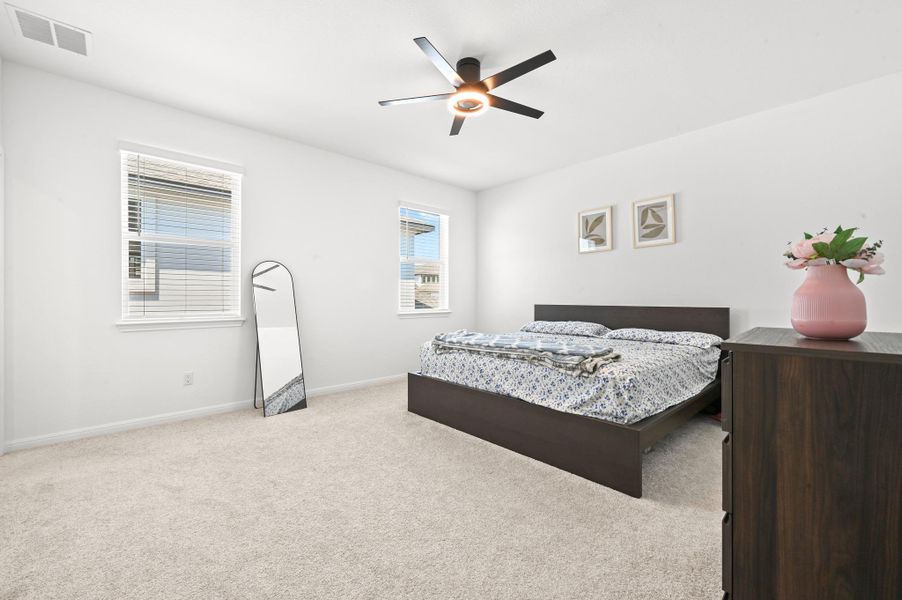 Plush carpeting and dual windows create a serene and airy atmosphere in this bedroom.