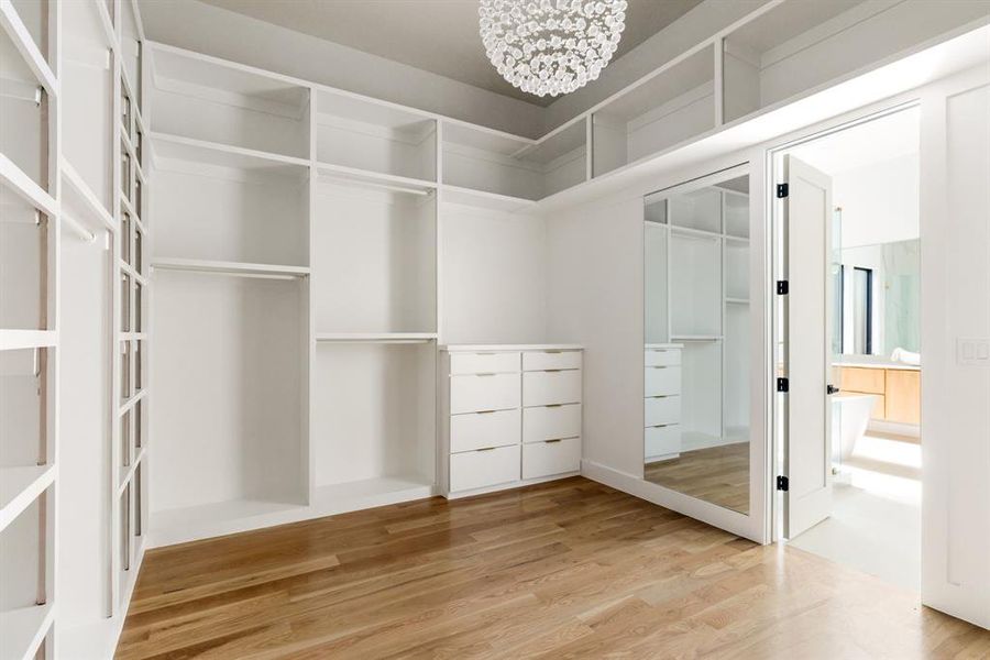 Spacious closet with a chandelier and wood finished floors Spacious closet with a chandelier and wood finished floors