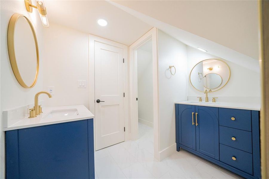 Bathroom featuring two vanities, marble look tiles, and recessed lighting Bathroom featuring two vanities, marble look tiles, and recessed lighting