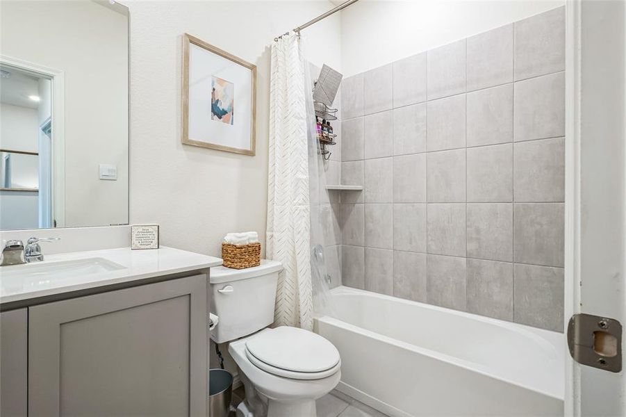 Bathroom with toilet, shower / bath combo with shower curtain, and vanity