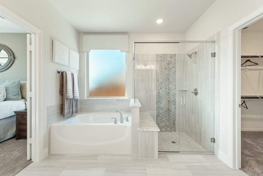 Master bathroom with soaking tub, glass-enclosed shower, and walk-in closet access