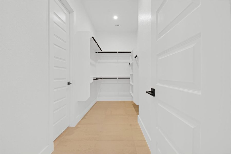 Second of two spacious walk-in closets in Primary Room with light tile patterned floors