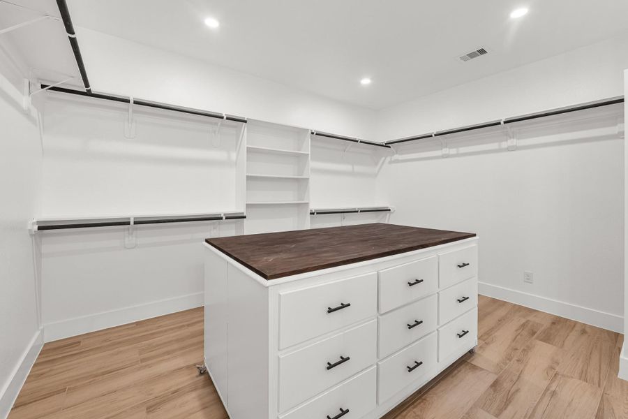 This spacious walk-in closet features ample hanging space, built-in shelves, and a central island with drawers, all set against a backdrop of sleek tile flooring and bright lighting. This spacious walk-in closet features ample hanging space, built-in shelves, and a central island with drawers, all set against a backdrop of sleek tile flooring and bright lighting.