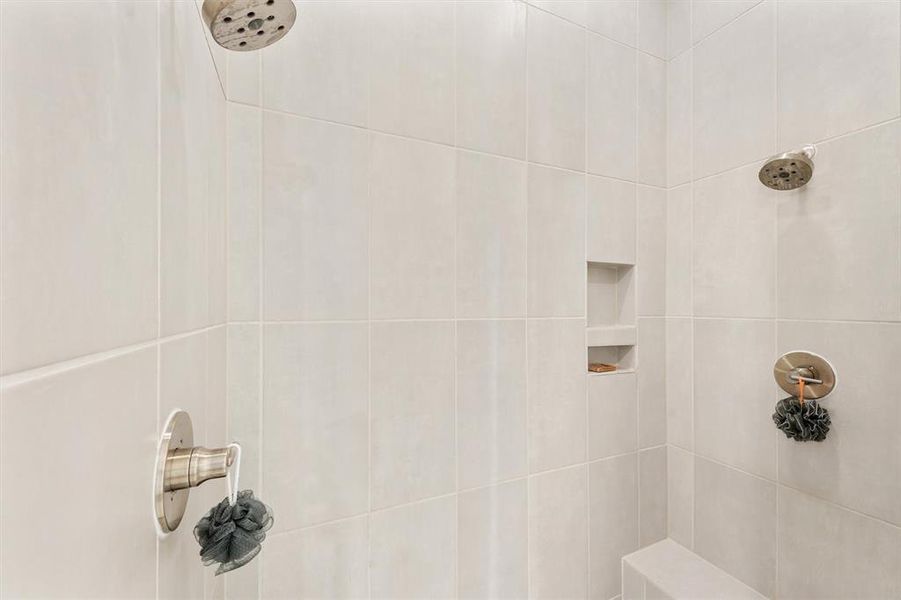 Dual showerheads and bench in the primary shower.