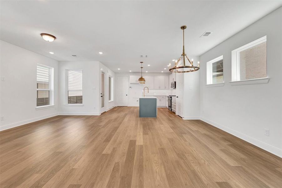 Open-concept living space featuring wood-finish flooring, white walls, and recessed lighting