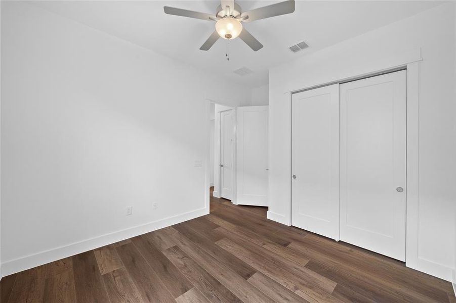 Interior room featuring wood-finish flooring, white walls, and a ceiling fan with integrated lighting