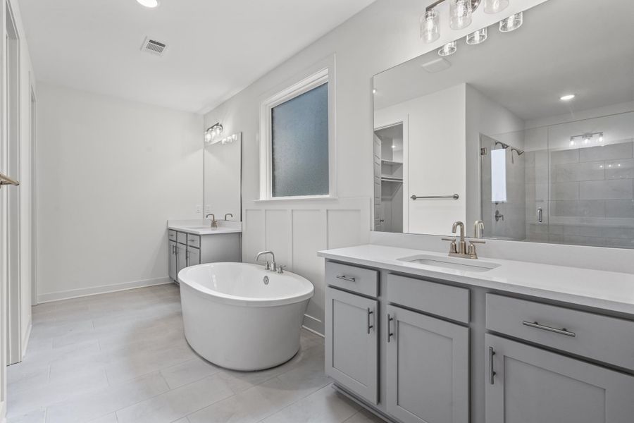 Bathroom with a shower stall, two vanities, a soaking tub, light tile patterned flooring, and recessed lighting