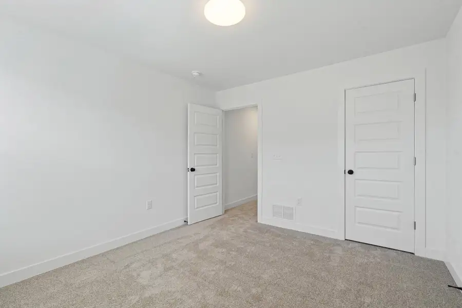 Spacious room featuring light gray carpet flooring, white painted walls, and white baseboards