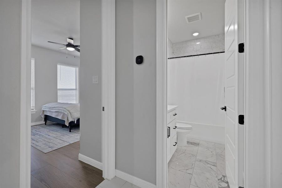 Full bathroom with marble finish floor, shower / bathtub combination with curtain, visible vents, and baseboards