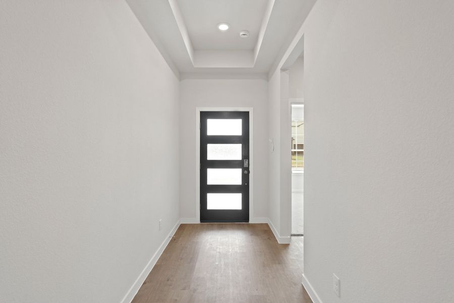 A hallway with a door and windows. A hallway with a door and windows.