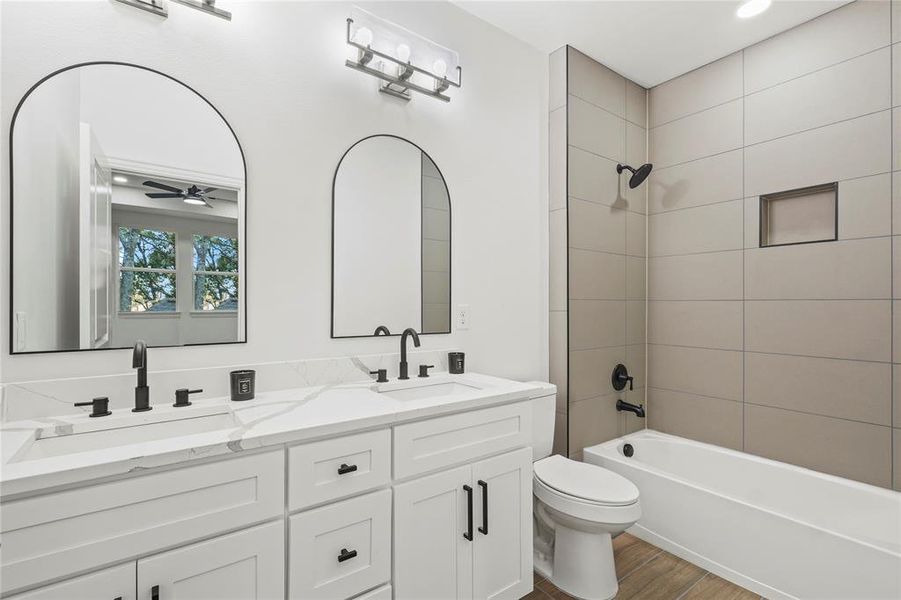 Full bath featuring  shower combination, double vanity, dark wood-type flooring, ceiling fan, and recessed lighting
