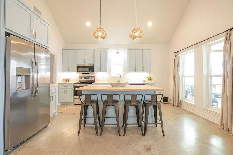 Kitchen featuring appliances with stainless steel finishes, a kitchen breakfast bar, pendant lighting, a center island, and tasteful backsplash