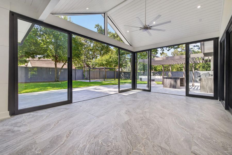 Light-filled sunroom space opens directly to the grounds through expansive walls of glass.