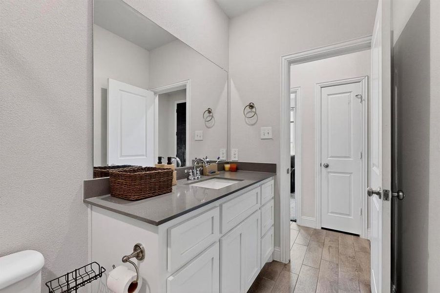Bathroom with vanity, light wood finished floors, and a textured wall Bathroom with vanity, light wood finished floors, and a textured wall