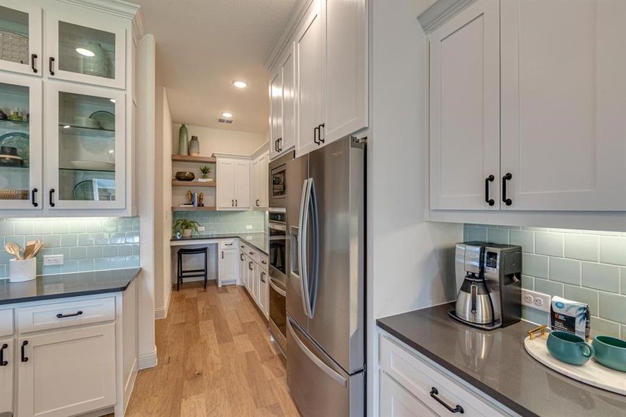 Kitchen featuring light hardwood / wood-style floors, appliances with stainless steel finishes, white cabinetry, and decorative backsplash