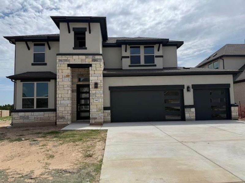 View of front facade with stone siding, stucco siding, and concrete driveway View of front facade with stone siding, stucco siding, and concrete driveway