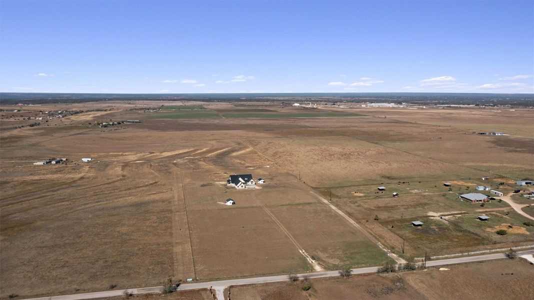 An aerial perspective reveals a charming farmhouse nestled within sprawling rural acreage. An aerial perspective reveals a charming farmhouse nestled within sprawling rural acreage.