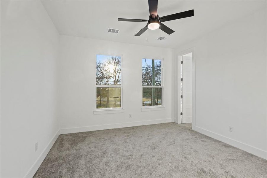 Empty room featuring a ceiling fan, visible vents, light carpet, and baseboards