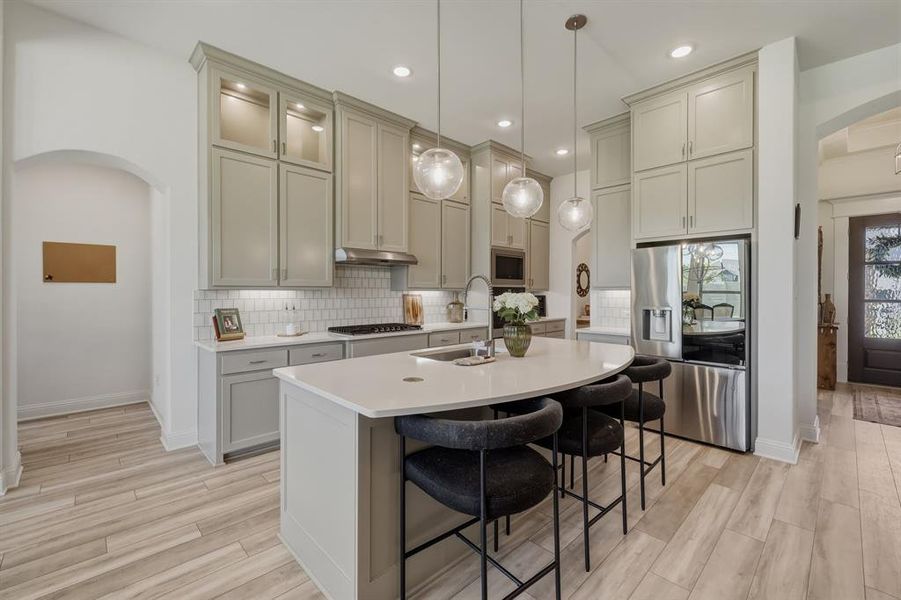 Beautiful open concept with painted cabinets to ceiling with lit uppers and curved quartz breakfast bar. Beautiful open concept with painted cabinets to ceiling with lit uppers and curved quartz breakfast bar.