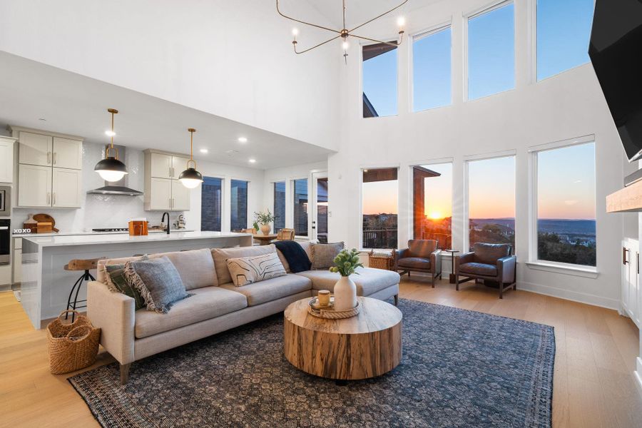 Spacious living area featuring high ceilings, light wood-finish flooring, and large windows Spacious living area featuring high ceilings, light wood-finish flooring, and large windows