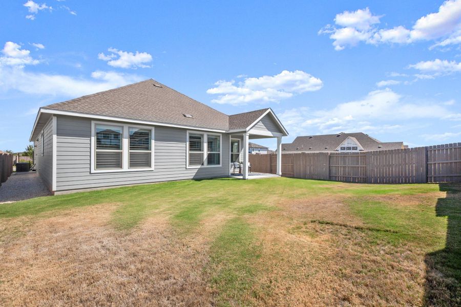 Rear view of property featuring a patio, a shingled roof, and a fenced backyard