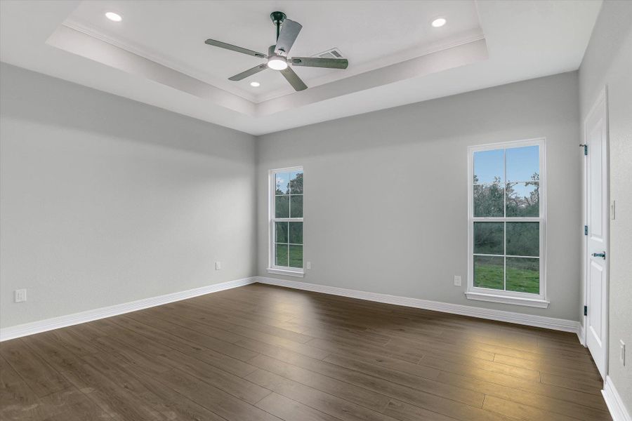 Empty room featuring dark wood-style floors, recessed lighting, ceiling fan, and a raised ceiling