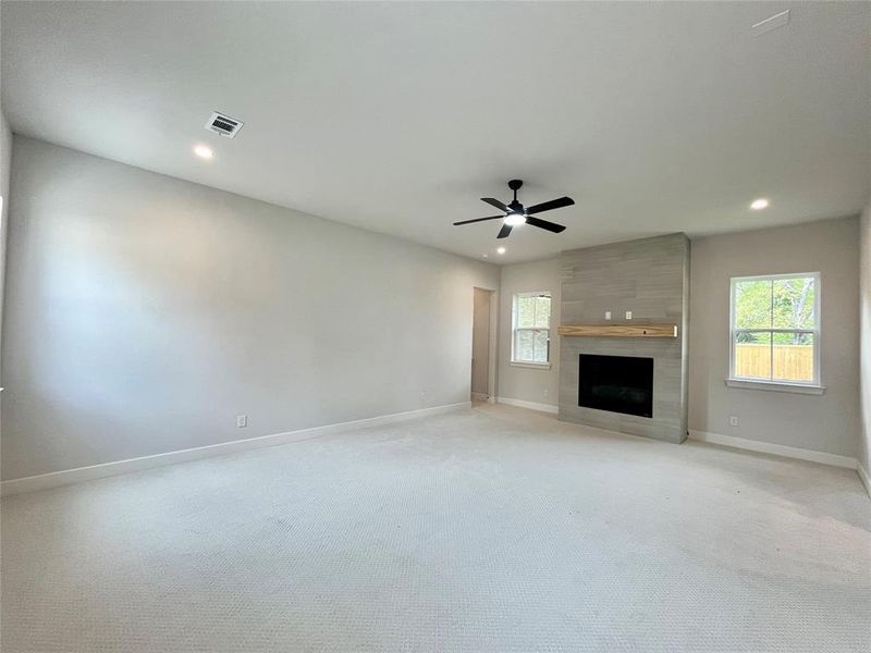 Unfurnished living room featuring light carpet, a fireplace, and ceiling fan