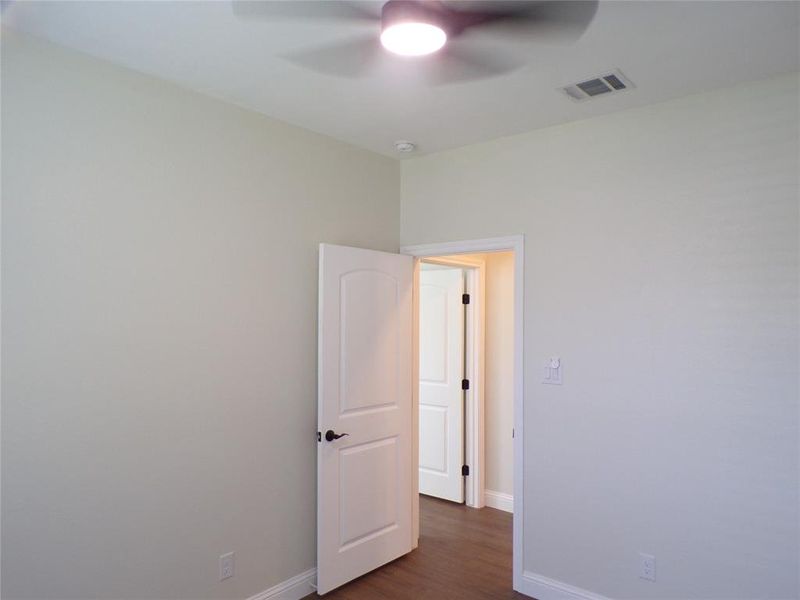 Unfurnished room featuring dark wood-type flooring and ceiling fan