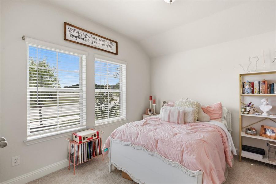 Bedroom featuring two large windows with horizontal blinds, neutral wall paint, vaulted ceiling, and carpet flooring