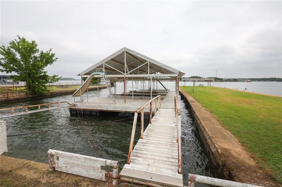 Dock area with a water view, a lawn, and boat lift Dock area with a water view, a lawn, and boat lift