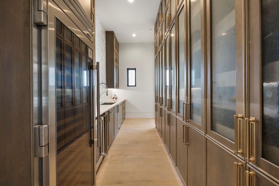 Gleaming wood floors lead down a well-appointed butler's pantry with integrated appliances and ample storage. Gleaming wood floors lead down a well-appointed butler's pantry with integrated appliances and ample storage.