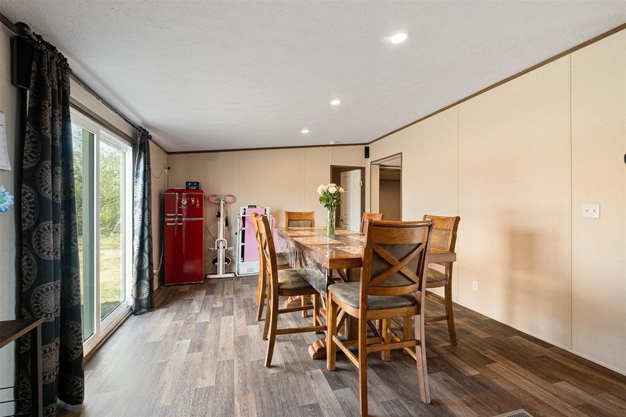 Dining area with crown molding, wood finished floors, recessed lighting, a decorative wall, and a textured ceiling