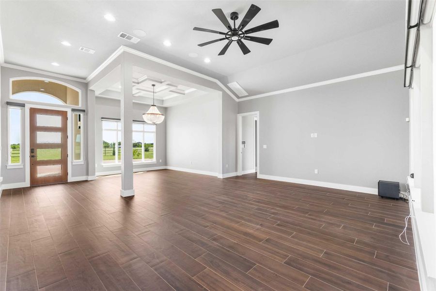 Unfurnished living room featuring dark wood-type flooring, ornamental molding, baseboards, ceiling fan, and recessed lighting Unfurnished living room featuring dark wood-type flooring, ornamental molding, baseboards, ceiling fan, and recessed lighting