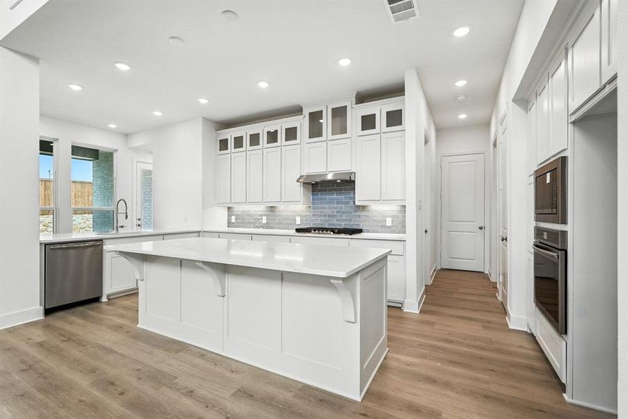 Kitchen with a center island, white cabinets, tasteful backsplash, appliances with stainless steel finishes, and recessed lighting Kitchen with a center island, white cabinets, tasteful backsplash, appliances with stainless steel finishes, and recessed lighting
