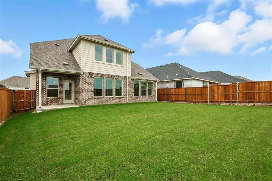 Rear view of house featuring roof with shingles, a fenced backyard, and brick siding