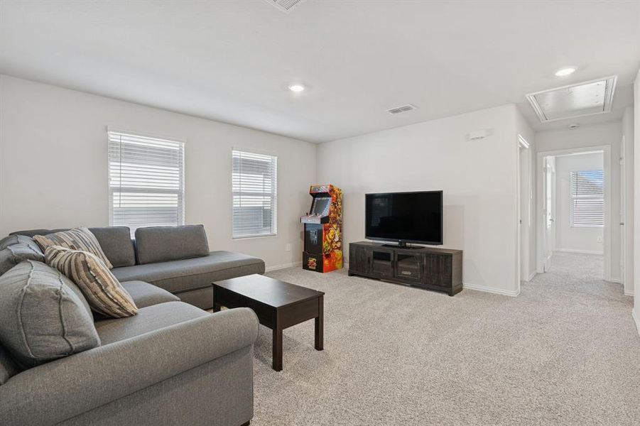 Living area with attic access, light carpet, and recessed lighting