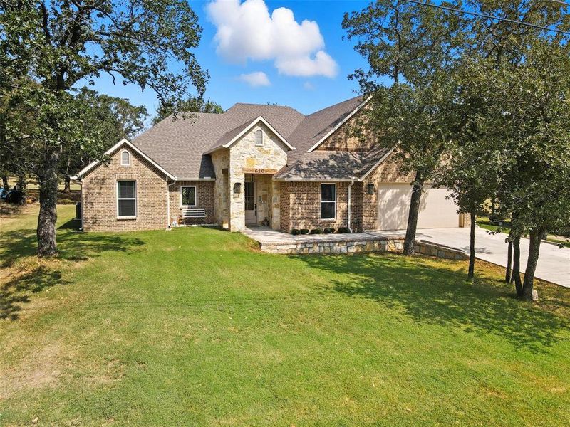 View of front facade with a front lawn, brick siding, driveway, and a shingled roof View of front facade with a front lawn, brick siding, driveway, and a shingled roof