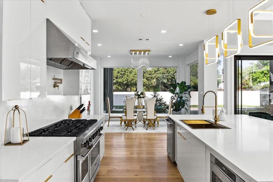 Kitchen with large sink, potfiller, designer pendants, and light hardwoods