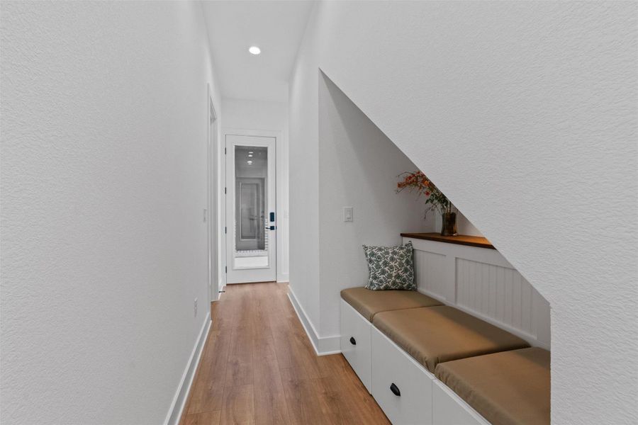 A well-lit hallway features rich hardwood flooring and a built-in storage bench for convenience. A well-lit hallway features rich hardwood flooring and a built-in storage bench for convenience.