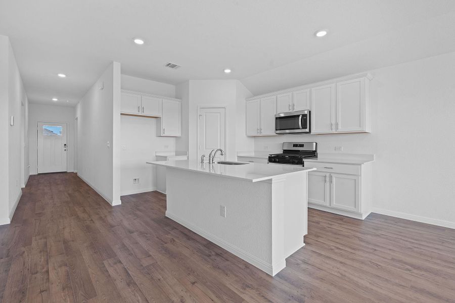 Kitchen with white cabinetry, recessed lighting, appliances with stainless steel finishes, dark wood-style floors, and a center island with sink